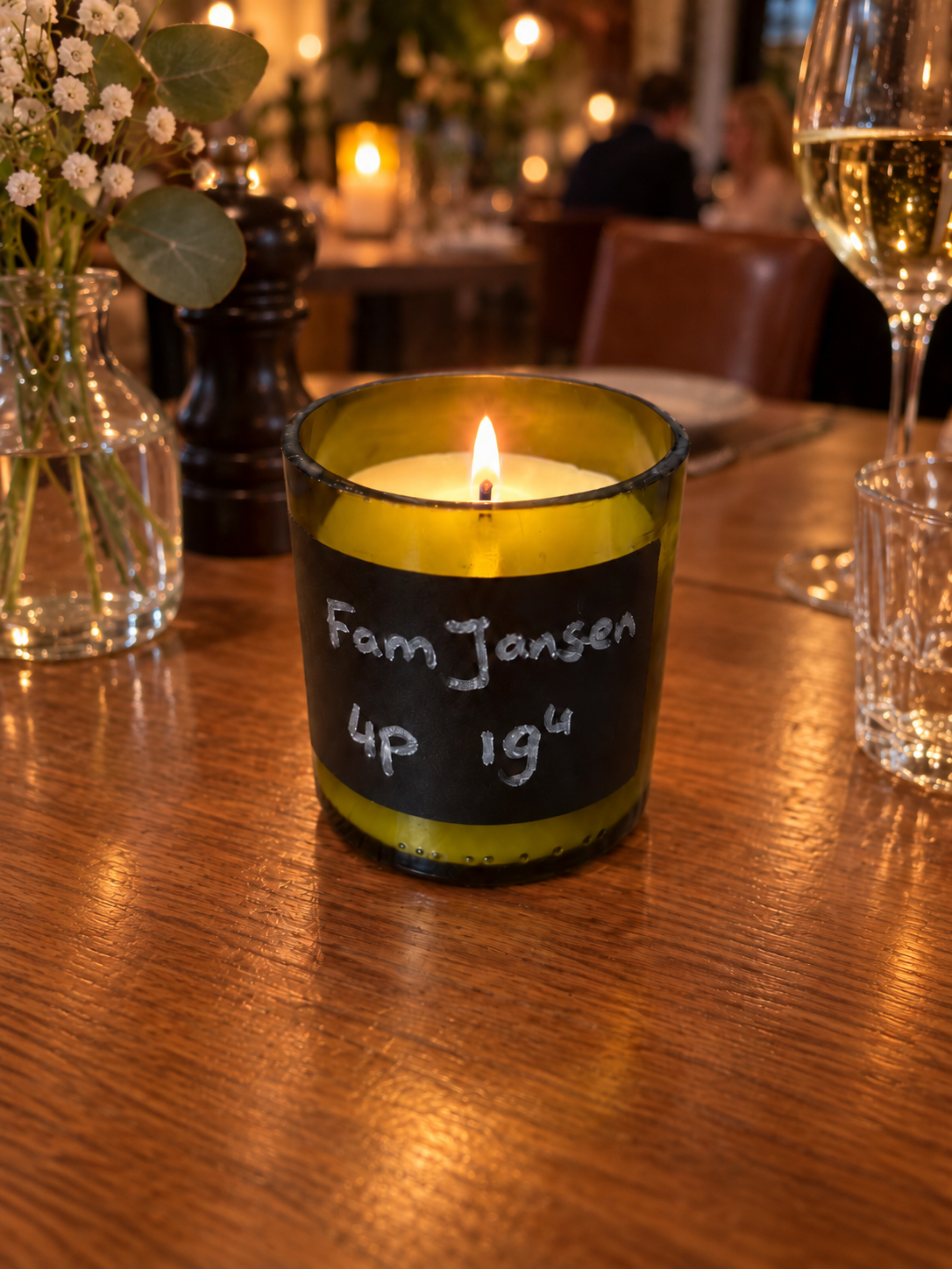 Kaars in een wijnfles met krijtbordetiket op een restauranttafel